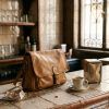 Bolso de piel suave con solapa apoyado sobre la barra de azulejos de un bar tradicional en Madrid.