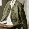 Detalle de una chaqueta liner acolchada en tono verde oliva con botones metálicos y acabado guateado.