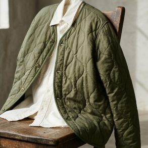 Detalle de una chaqueta liner acolchada en tono verde oliva con botones metálicos y acabado guateado.