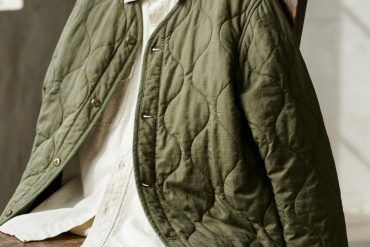 Detalle de una chaqueta liner acolchada en tono verde oliva con botones metálicos y acabado guateado.