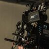 Cámara de cine profesional en un set de rodaje iluminado con sombras dramáticas y atmósfera cinematográfica.