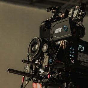 Cámara de cine profesional en un set de rodaje iluminado con sombras dramáticas y atmósfera cinematográfica.