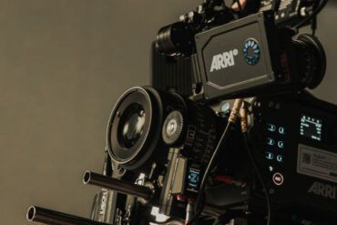 Cámara de cine profesional en un set de rodaje iluminado con sombras dramáticas y atmósfera cinematográfica.