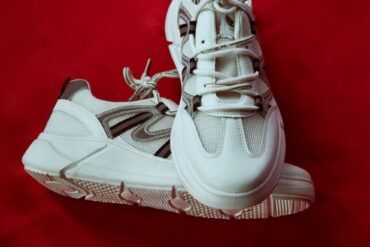 Zapatillas clásicas de piel blanca sobre suelo de galería de arte con luz natural lateral