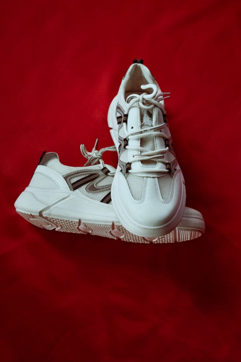 Zapatillas clásicas de piel blanca sobre suelo de galería de arte con luz natural lateral