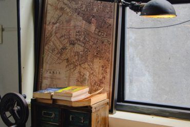 Escritorio clásico con máquina de escribir vintage, libros apilados y notas manuscritas con luz de ventana.