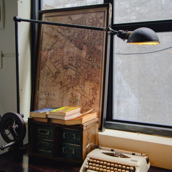 Escritorio clásico con máquina de escribir vintage, libros apilados y notas manuscritas con luz de ventana.