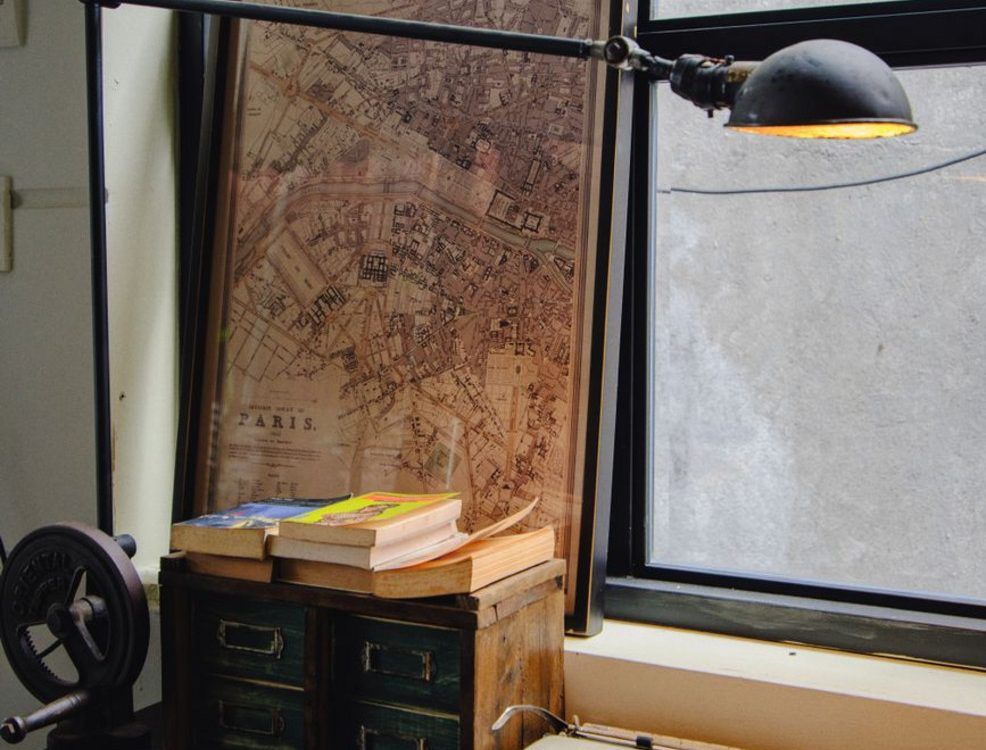 Escritorio clásico con máquina de escribir vintage, libros apilados y notas manuscritas con luz de ventana.