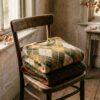Prendas de punto dobladas con estampado de rombos otoñal sobre una silla de madera con luz natural