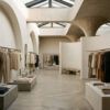 Interior contemporáneo y minimalista de una tienda de moda con percheros diáfanos y arquitectura elegante.