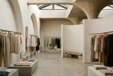 Interior contemporáneo y minimalista de una tienda de moda con percheros diáfanos y arquitectura elegante.