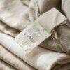Primer plano de etiquetas de composición y lavado cosidas en el interior de una prenda de tela natural doblada con cuidado