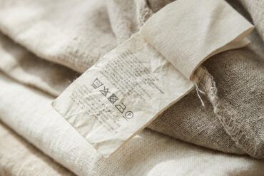 Primer plano de etiquetas de composición y lavado cosidas en el interior de una prenda de tela natural doblada con cuidado