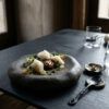 Mesa minimalista de alta gastronomía con vajilla vanguardista y estética editorial contemporánea con luz suave natural.