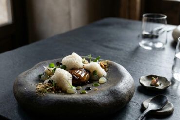 Mesa minimalista de alta gastronomía con vajilla vanguardista y estética editorial contemporánea con luz suave natural.