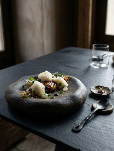 Mesa minimalista de alta gastronomía con vajilla vanguardista y estética editorial contemporánea con luz suave natural.
