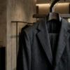 Detalle de sastrería masculina elegante con chaqueta de lana y percha de madera en boutique contemporánea