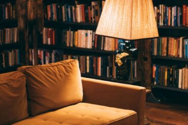 Salón acogedor con gran librería de madera repleta de libros y dos sillones de cuero iluminados con luz natural