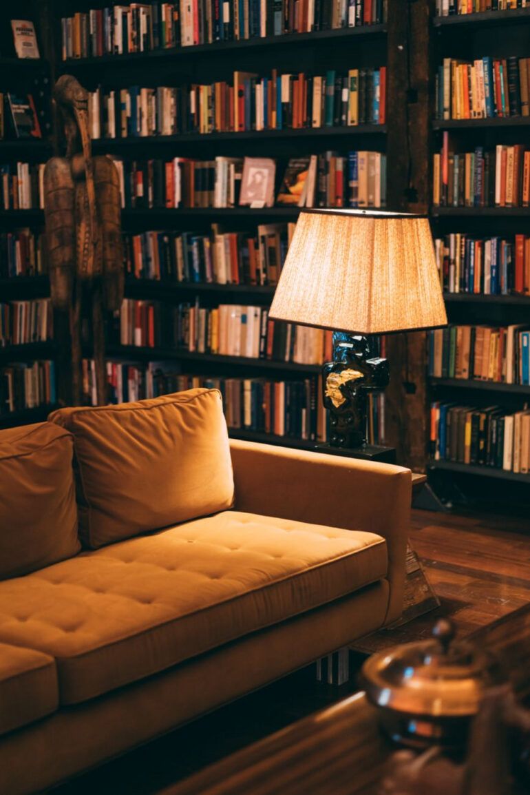 Salón acogedor con gran librería de madera repleta de libros y dos sillones de cuero iluminados con luz natural