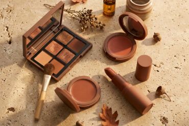 Bodegón editorial con productos de maquillaje de otoño en tonos cálidos, sombras terracota y coloretes sobre fondo neutro