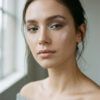 Primer plano editorial de mujer con maquillaje en tonos fríos, piel luminosa y sombra plateada suave.