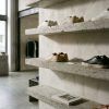 Zapatillas urbanas ordenadas en baldas minimalistas de hormigón con iluminación natural de estudio.