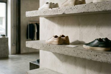 Zapatillas urbanas ordenadas en baldas minimalistas de hormigón con iluminación natural de estudio.