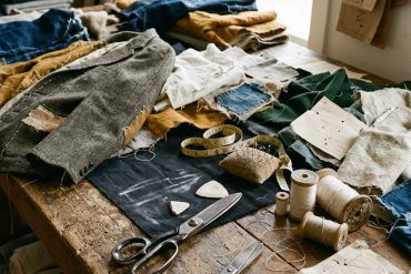 Tejidos reciclados y patrones de sastrería sobre una mesa de corte en un taller de confección textil