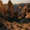 Cañón árido y formaciones rocosas al atardecer bajo un cielo despejado en el desierto