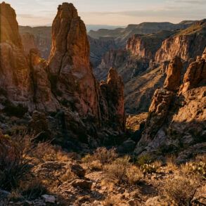 Cañón árido y formaciones rocosas al atardecer bajo un cielo despejado en el desierto