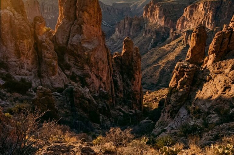 Cañón árido y formaciones rocosas al atardecer bajo un cielo despejado en el desierto