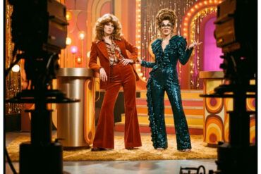 Escena editorial de inspiración retro pop con dos mujeres en un plató de televisión vintage con luces cálidas
