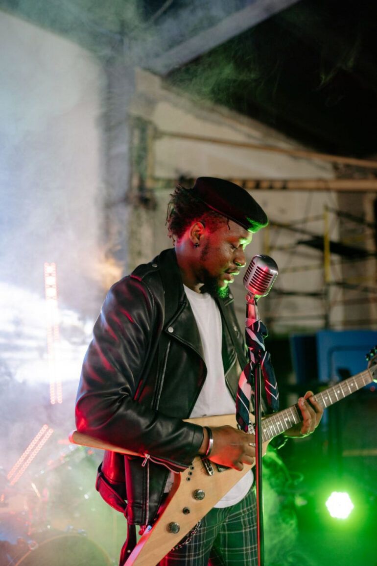 Micrófono clásico sobre un escenario oscuro iluminado con luces tenues de concierto de rock y poesía