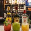 Barra elegante de coctelería con copas de cristal y botellas de destilados bajo luz cálida editorial.
