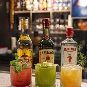 Barra elegante de coctelería con copas de cristal y botellas de destilados bajo luz cálida editorial.