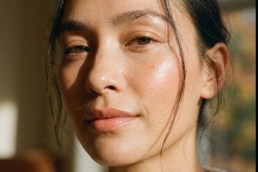 Primer plano de rostro femenino con piel luminosa y cuidada, iluminado por luz solar suave otoñal.