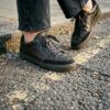 Zapatillas urbanas de cuero negro sobre el asfalto de la ciudad con luz natural