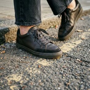 Zapatillas urbanas de cuero negro sobre el asfalto de la ciudad con luz natural