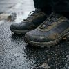 Detalle de zapatillas urbanas técnicas sobre suelo de asfalto mojado en la ciudad
