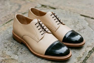 Primer plano cenital de zapatos bicolor de piel sobre suelo urbano limpio con luz natural de otoño